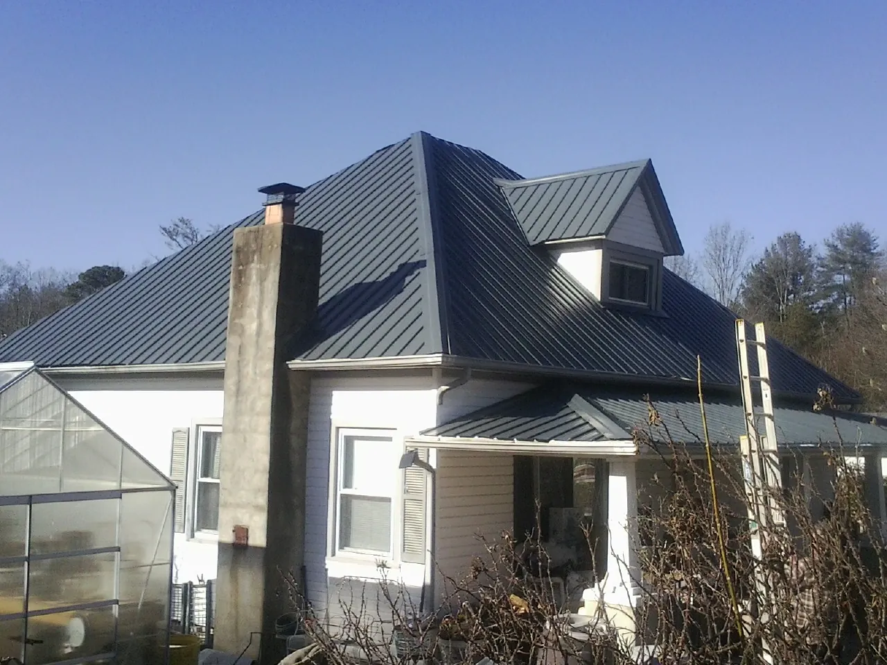 Dark blue standing seam metal roof on a white farmhouse with dormer — Slate & Tile Roof Repair by Roofing Brothers in Dilworth
