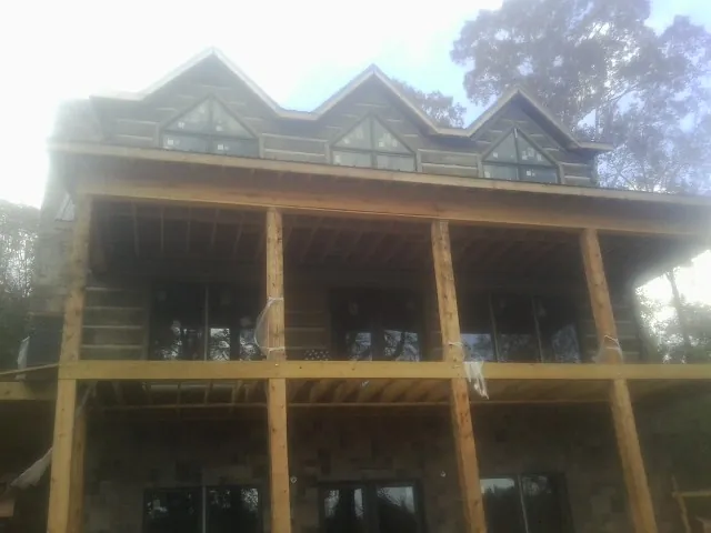 Dormers and porch framing on a large log home under construction — Roof Coating work by our crew in Dilworth