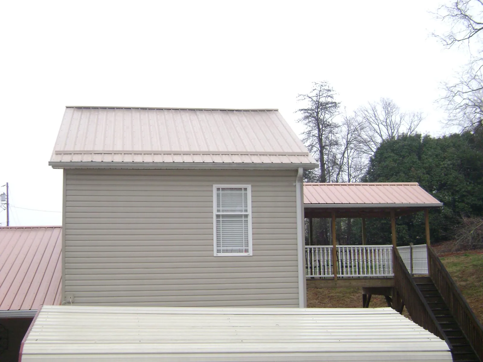 Tan metal roofs on a two story addition and attached porch, from a Roof Replacement job in Dilworth
