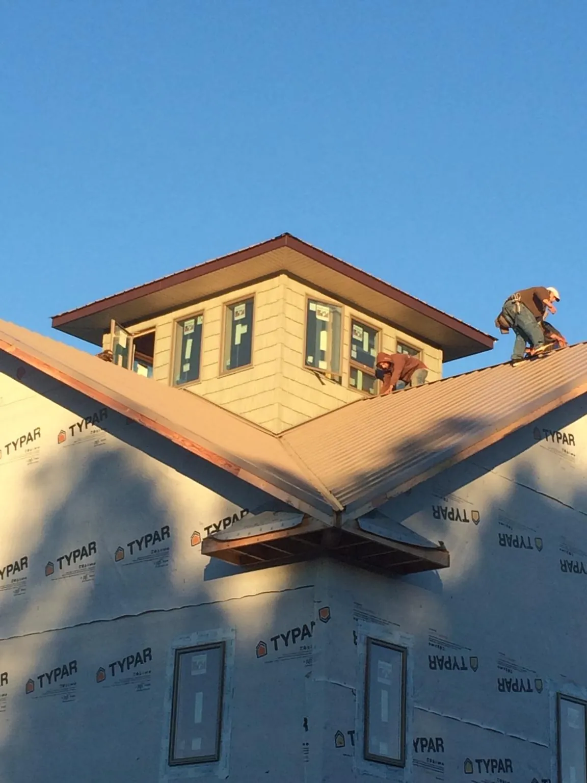 Roofers working around a rooftop cupola on a new metal roof at sunset — Roof Waterproofing in Dilworth by Roofing Brothers